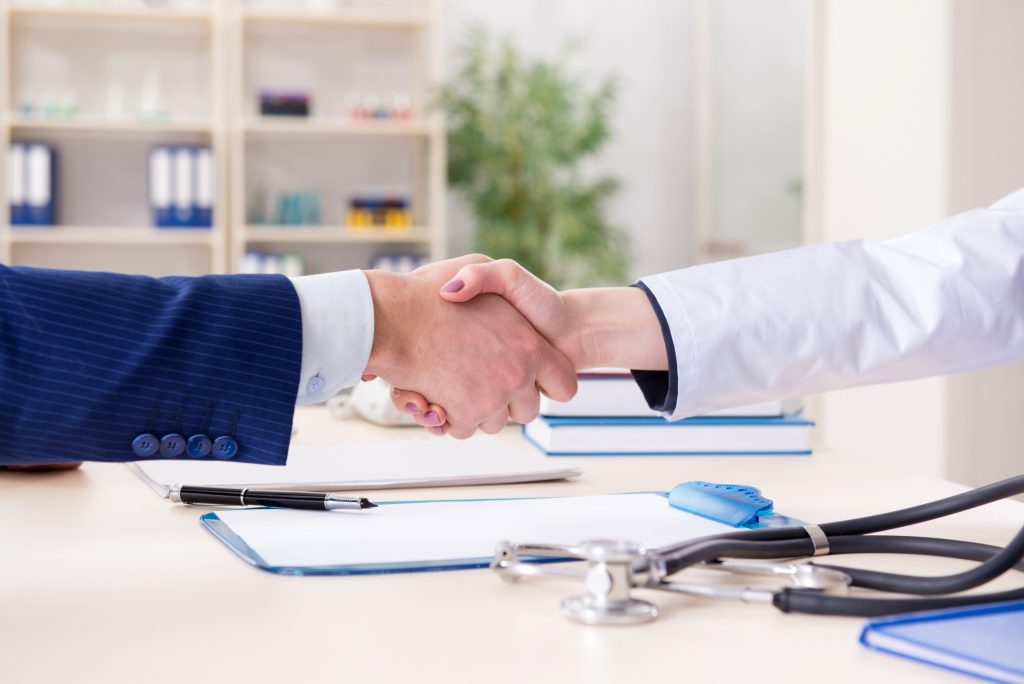 Doctor shaking hands over agreement.