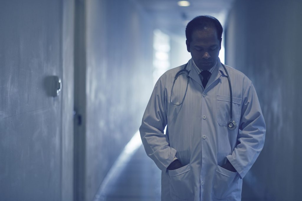 Physician in a dark hallway looking sad